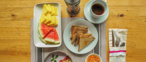 A wooden table with breakfast items including toast, fruit, and a coffee pot.