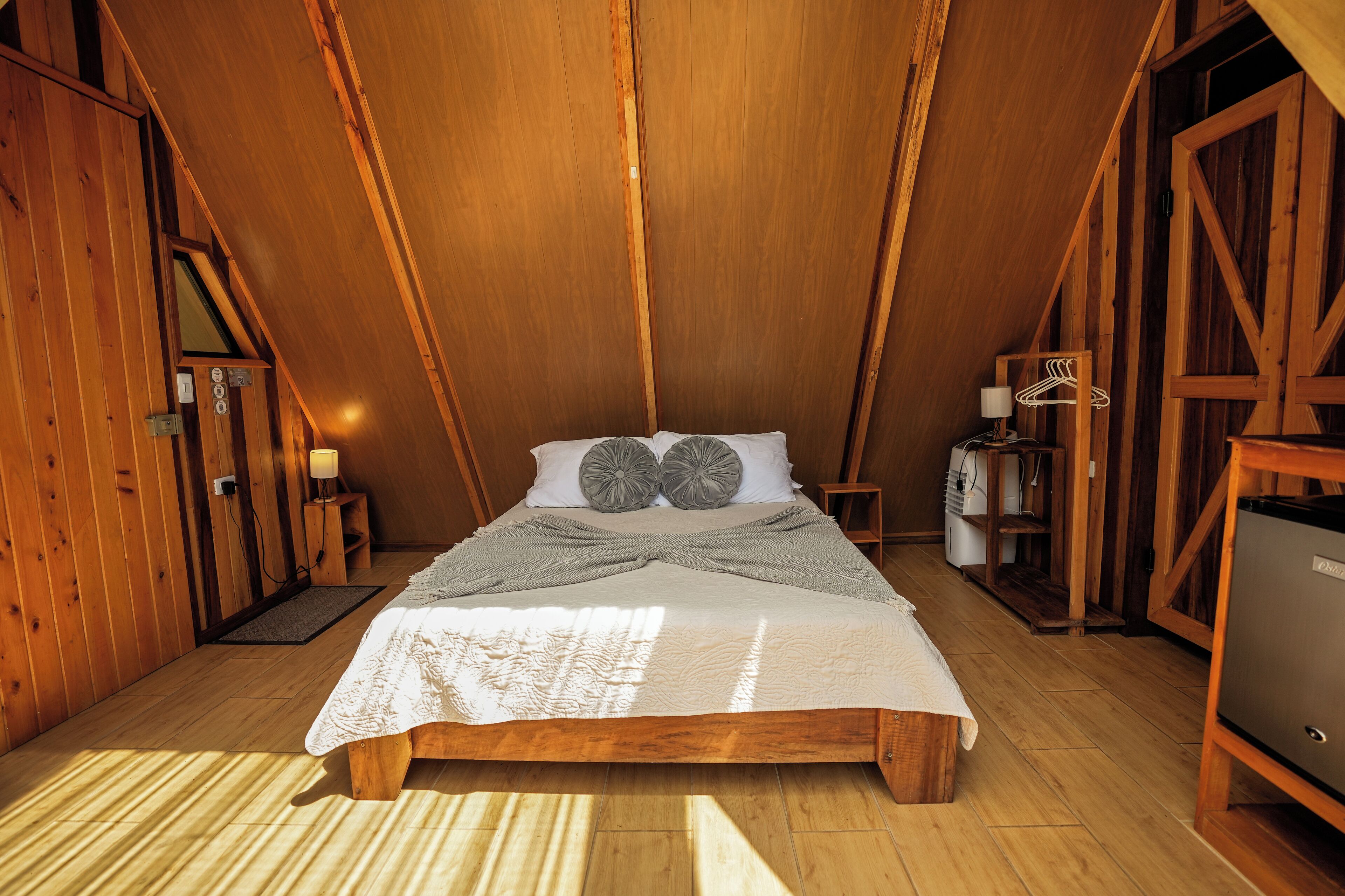 A wooden room with a bed, a desk, and a chair.