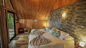 Una habitación con paneles de madera, una pared de piedra, una cama con manta y una mesita de noche con lámpara.