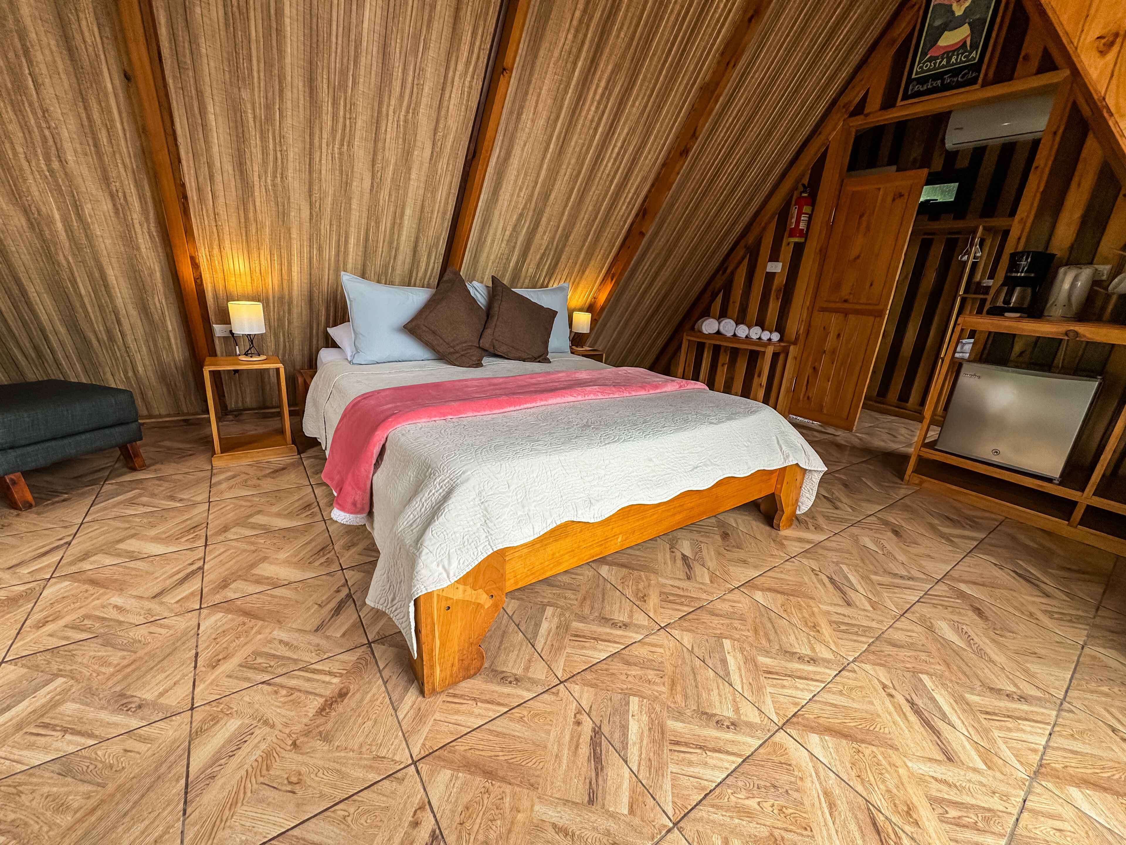 Un dormitorio acogedor con una cama de madera, una mesita de noche pequeña y un banco.