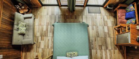 A compact room with a bed, a sofa, and a small table with a television.
