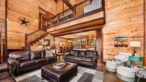 Ein geräumiges Wohnzimmer mit Ledersofas, einem Couchtisch und einer Treppe, die zu einer oberen Ebene führt.