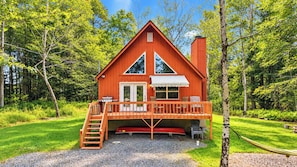 A cabin with a deck, a staircase, and a grill.