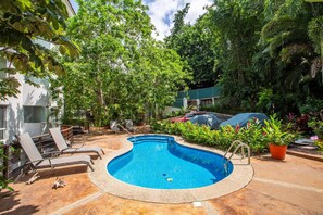 Una piscina con sillones de descanso y plantas en macetas alrededor.
