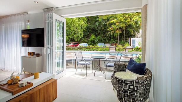 A modern living room with a TV, a wooden coffee table, and a seating area with a patterned ottoman. - Peaceful Oasis in Romantic Zone w/ Pool & Parking (Puerto Vallarta)