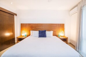 Habitación de hotel con una cama grande, cabecera de madera, dos mesitas de noche con lámparas y un armario.