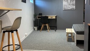 Una habitación con escritorio, silla, cama y un pequeño taburete.