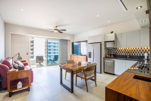 En moderne opholdsstue med spiseplads, køkken og en balkon med udsigt.
