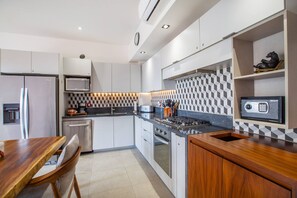 Een moderne keuken met roestvrijstalen apparatuur, een houten eettafel en een achterwand met een patroon.