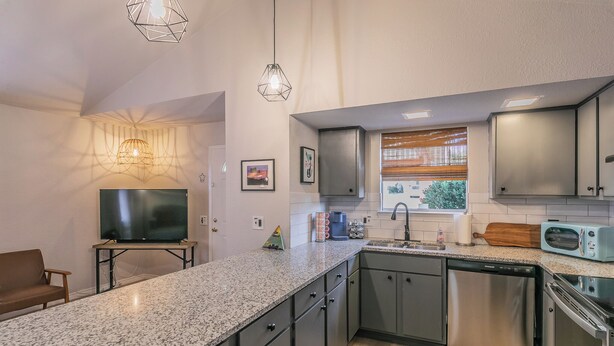 A modern kitchen with granite countertops, stainless steel appliances, and pendant lighting. - No Cleaning Fee!!~King Bed~Near Dickies,TCU, cultural district~Sleeps 6 (Fort Worth)