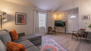 A modern living room with a grey sofa, a TV, and a small table. - No Cleaning Fee!!~King Bed~Near Dickies,TCU, cultural district~Sleeps 6 (Fort Worth)