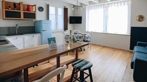 Una cocina moderna con armarios de madera, un refrigerador azul y un comedor con mesa y sillas de madera.