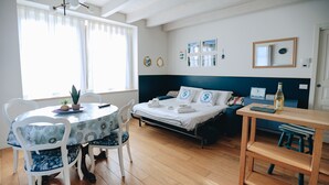Una habitación con cama, una mesa, sillas, un escritorio pequeño y una ventana.