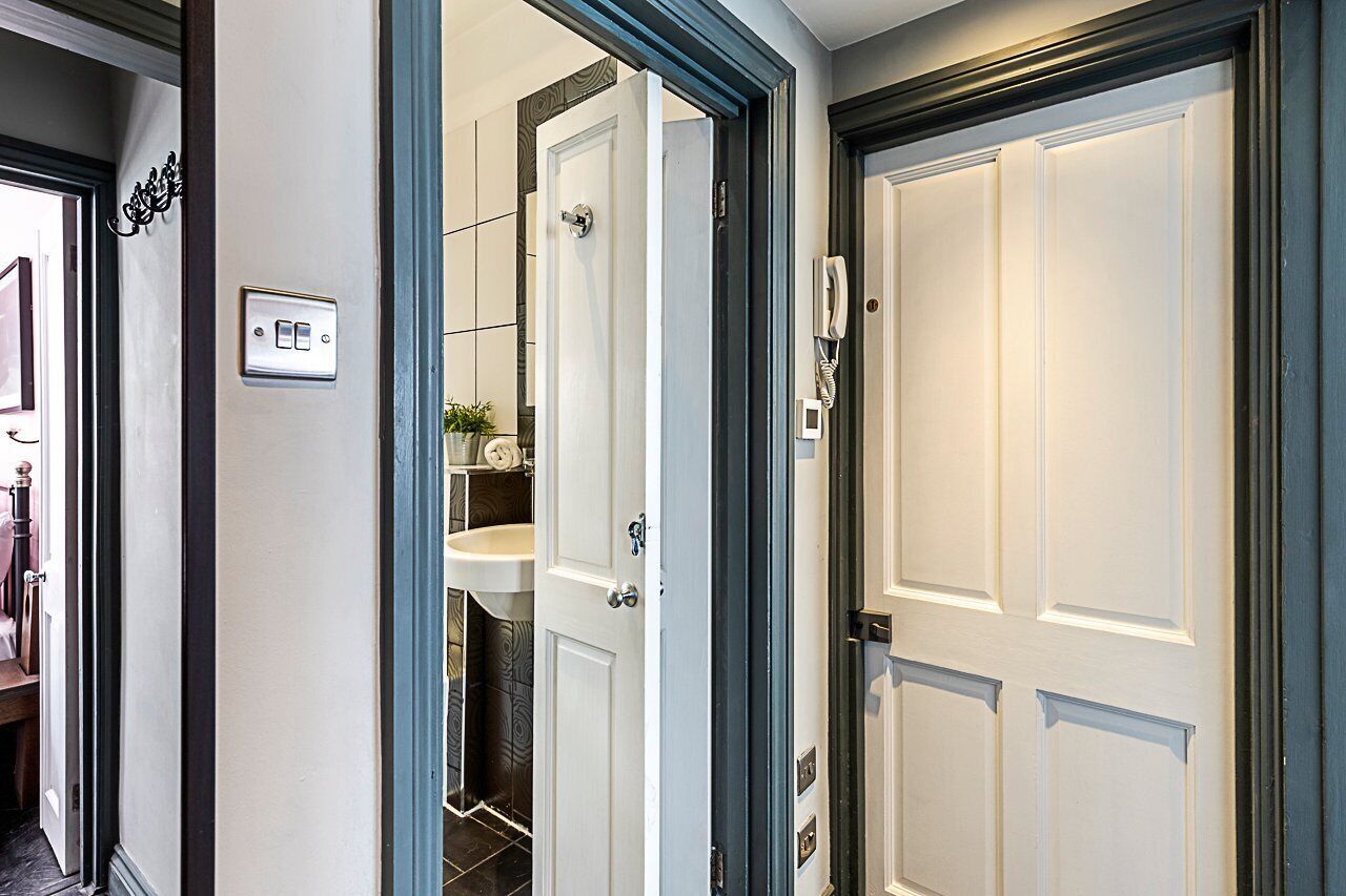 A hallway with a white door, a light switch, and a telephone.