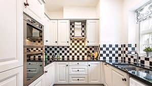 Une cuisine moderne avec des meubles blancs, un dosseret à carreaux noirs et blancs, des appareils en acier inoxydable et un lave-vaisselle intégré.
