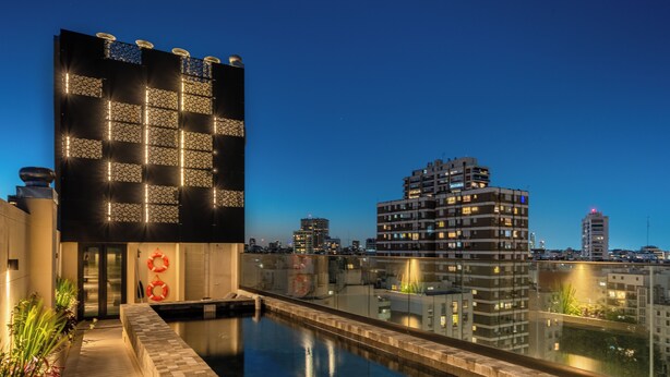 A modern building with a pool and a city view at dusk. - Vilon Recoleta Hotel (Buenos Aires)
