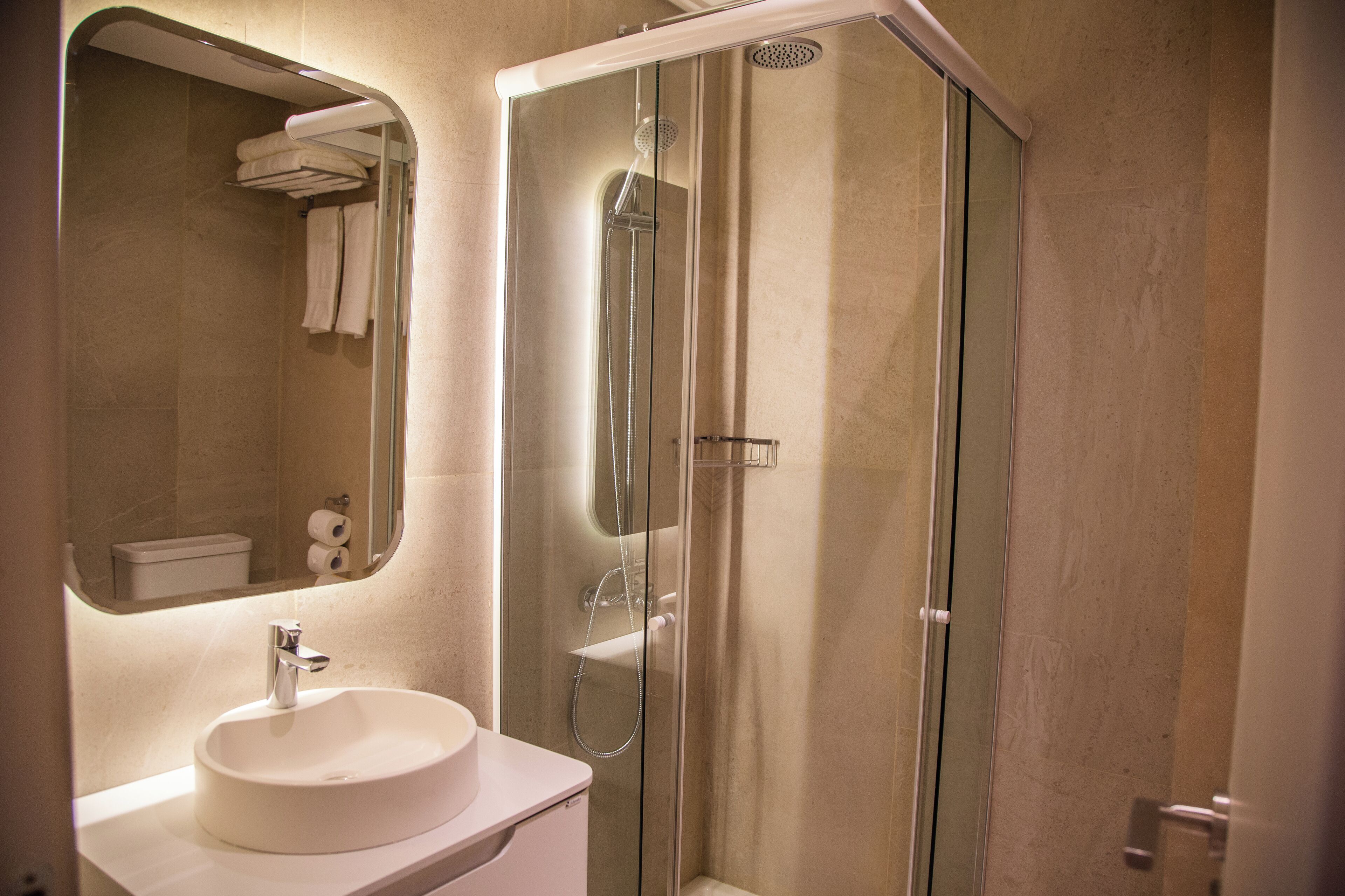 A modern bathroom with a glass-enclosed shower, a white sink, and a mirror above the sink.