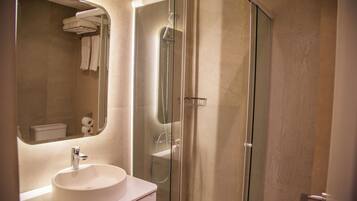 A modern bathroom with a glass-enclosed shower, a white sink, and a mirror above the sink.