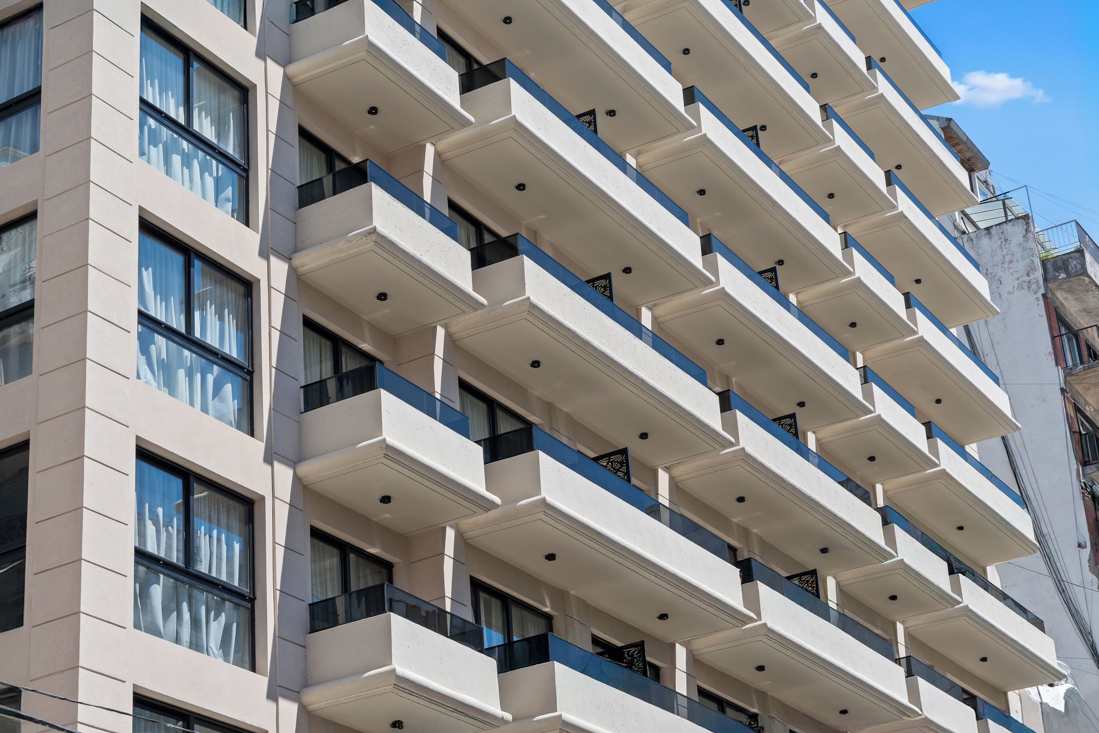 A multi-story building with a uniform facade, featuring balconies with railings and windows.