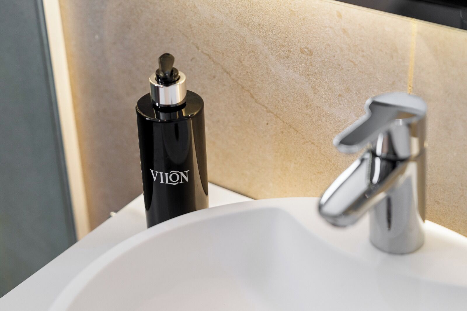 A bathroom sink with a modern faucet and a black bottle labeled "VION" on the counter.