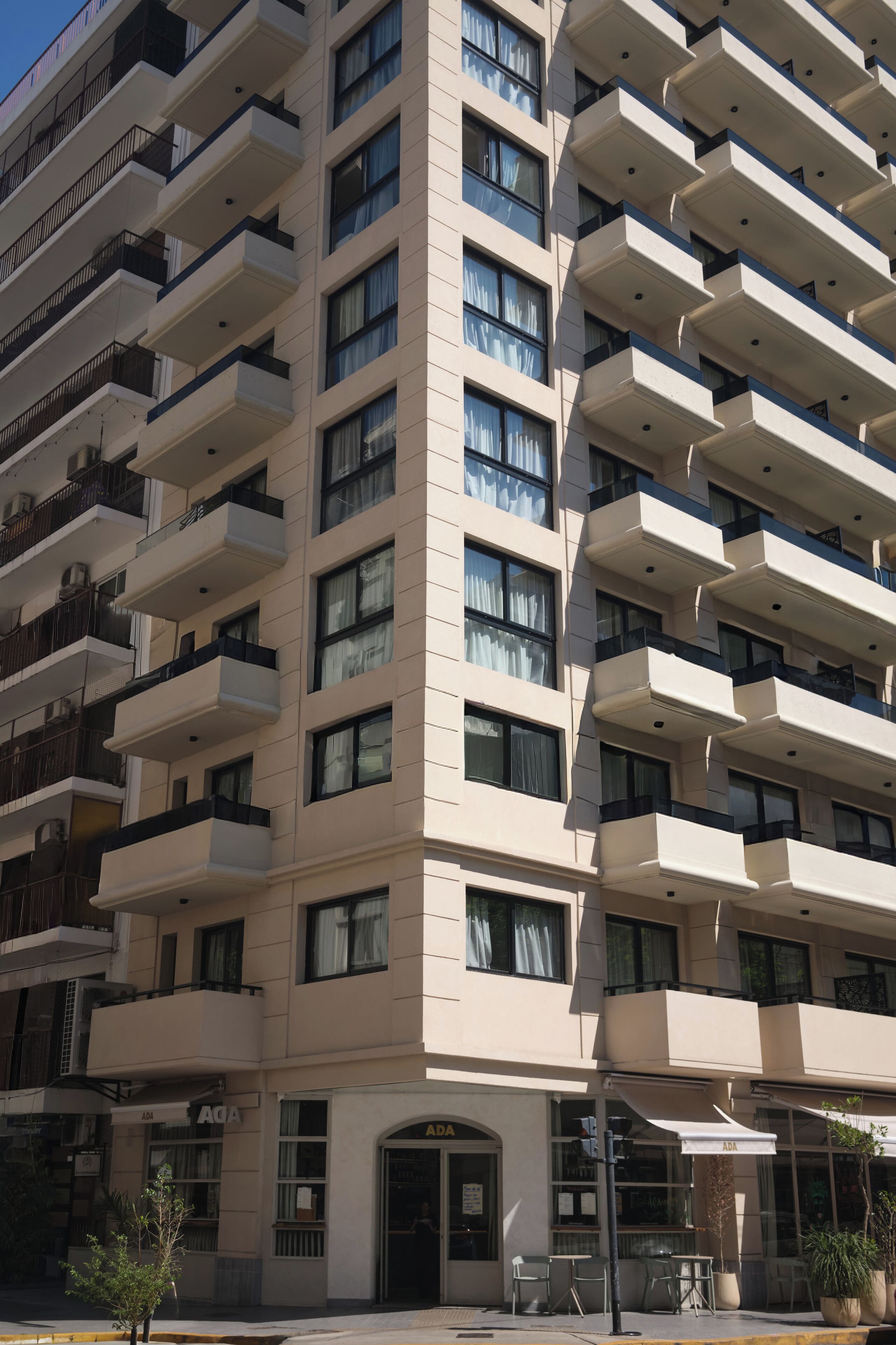 A multi-story hotel with balconies, a storefront, and outdoor seating.