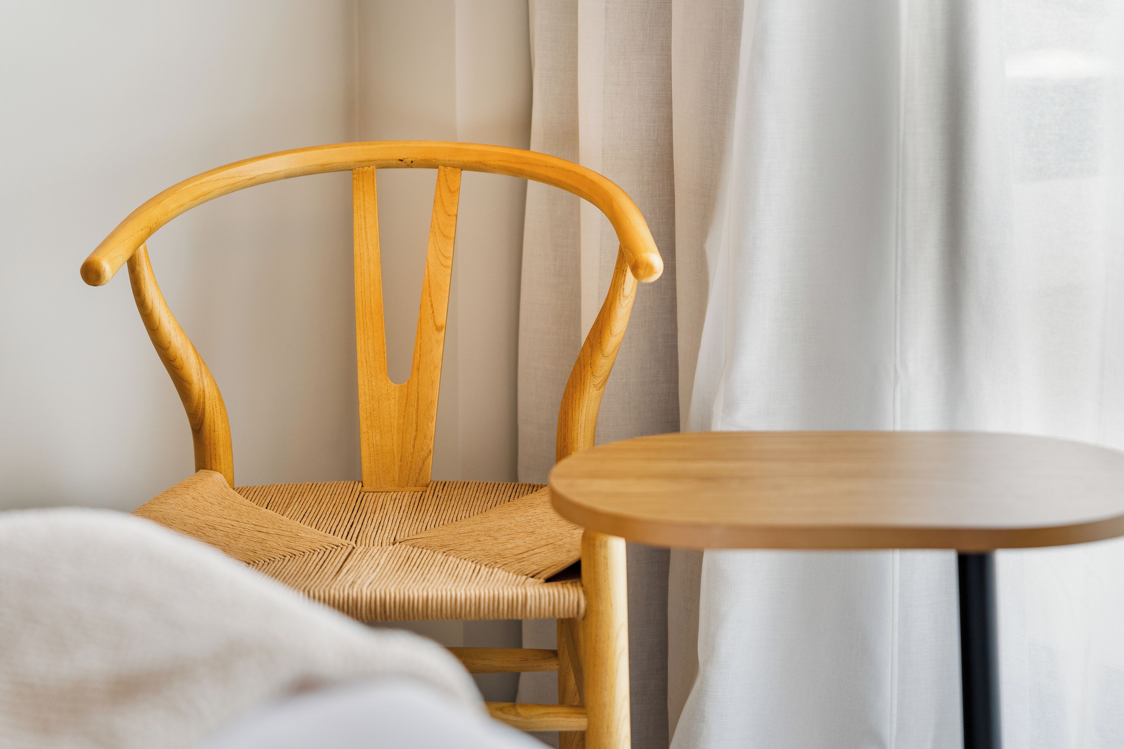 A wooden chair with a woven seat and backrest, positioned next to a round wooden table.