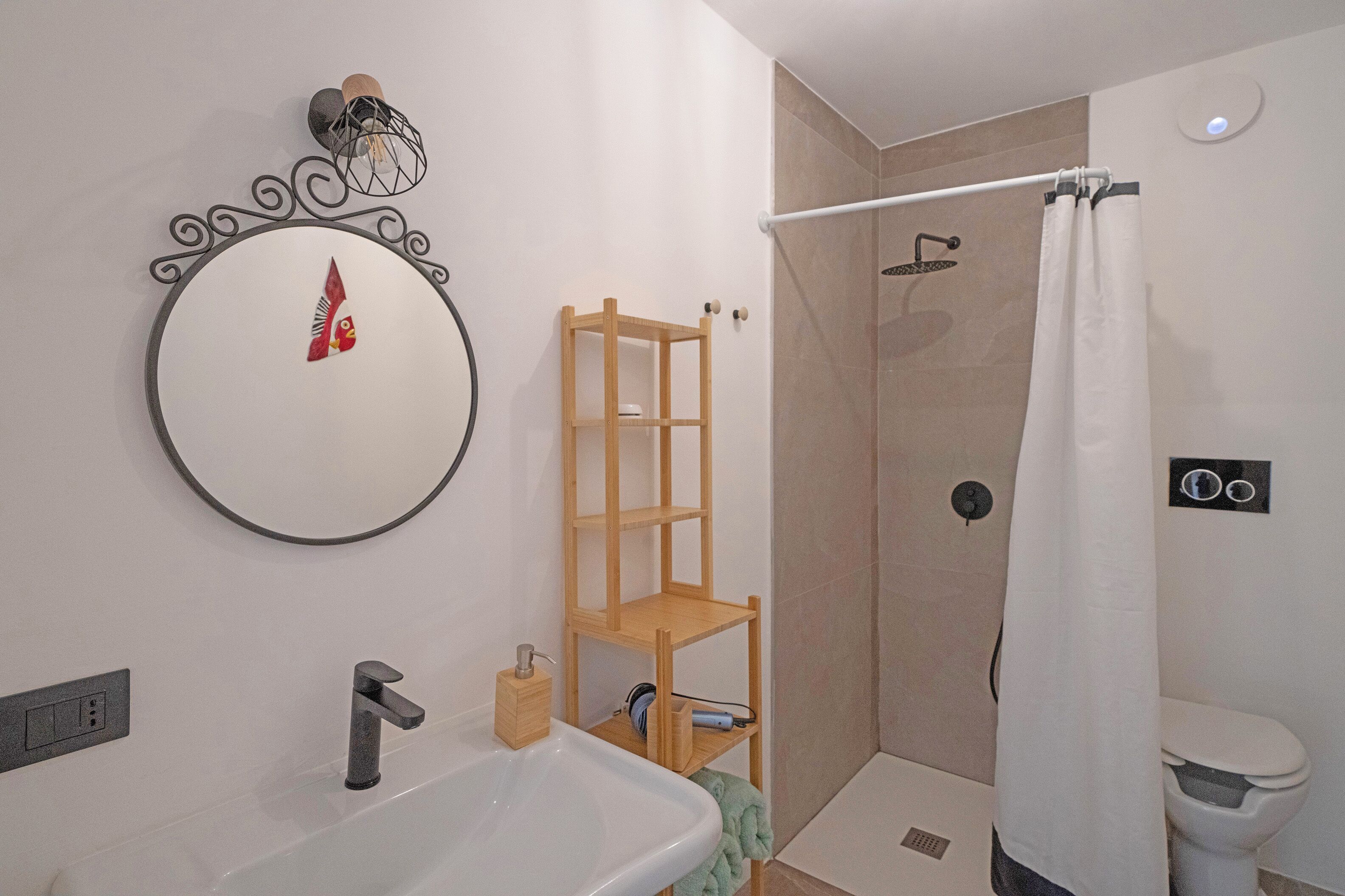 Un baño con lavamanos, espejo, ducha e inodoro.