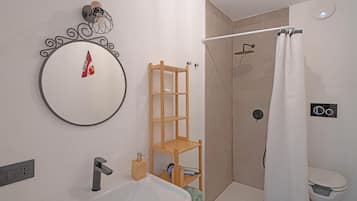 Un baño con lavamanos, espejo, ducha e inodoro.