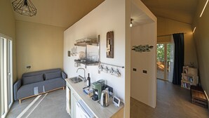 Una cocina moderna con horno integrado, cafetera y lavabo. En la sala de estar, hay un sofá gris y una mesa de centro de madera.