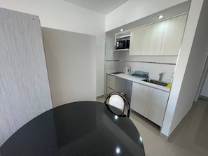 A modern kitchen with white cabinets, a black countertop, and a microwave. - Luxurious Studio In San Telmo-paseo De La Cisterna (Buenos Aires)