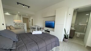 A modern bedroom with a large bed, a TV, a desk, and a bathroom. - Luxury and Comfort in San Telmo With Pool and Balcony (Buenos Aires)