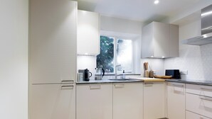 Een moderne keuken met witte kasten, een roestvrijstalen afzuigkap en een raam met uitzicht op bomen.