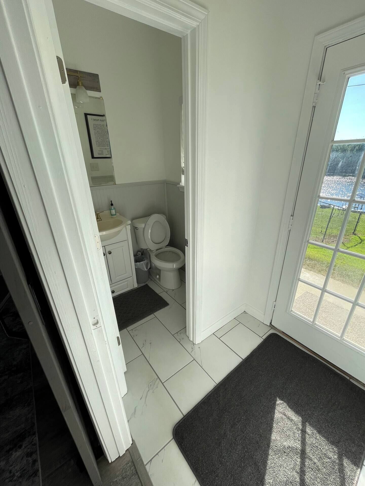 A bathroom with a toilet, sink, and a small window.