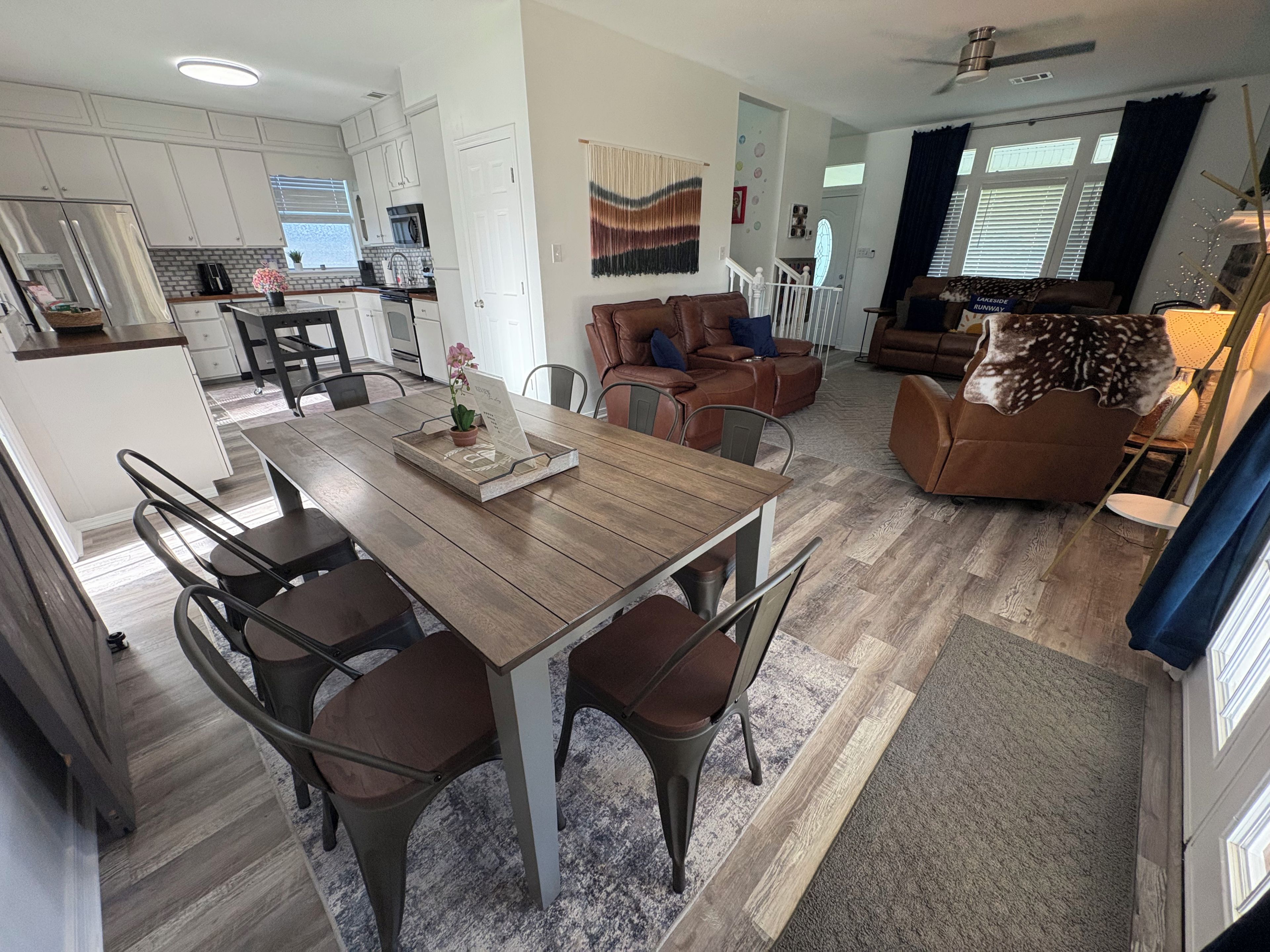 A spacious living area with a wooden dining table, leather sofas, and a kitchen in the background.