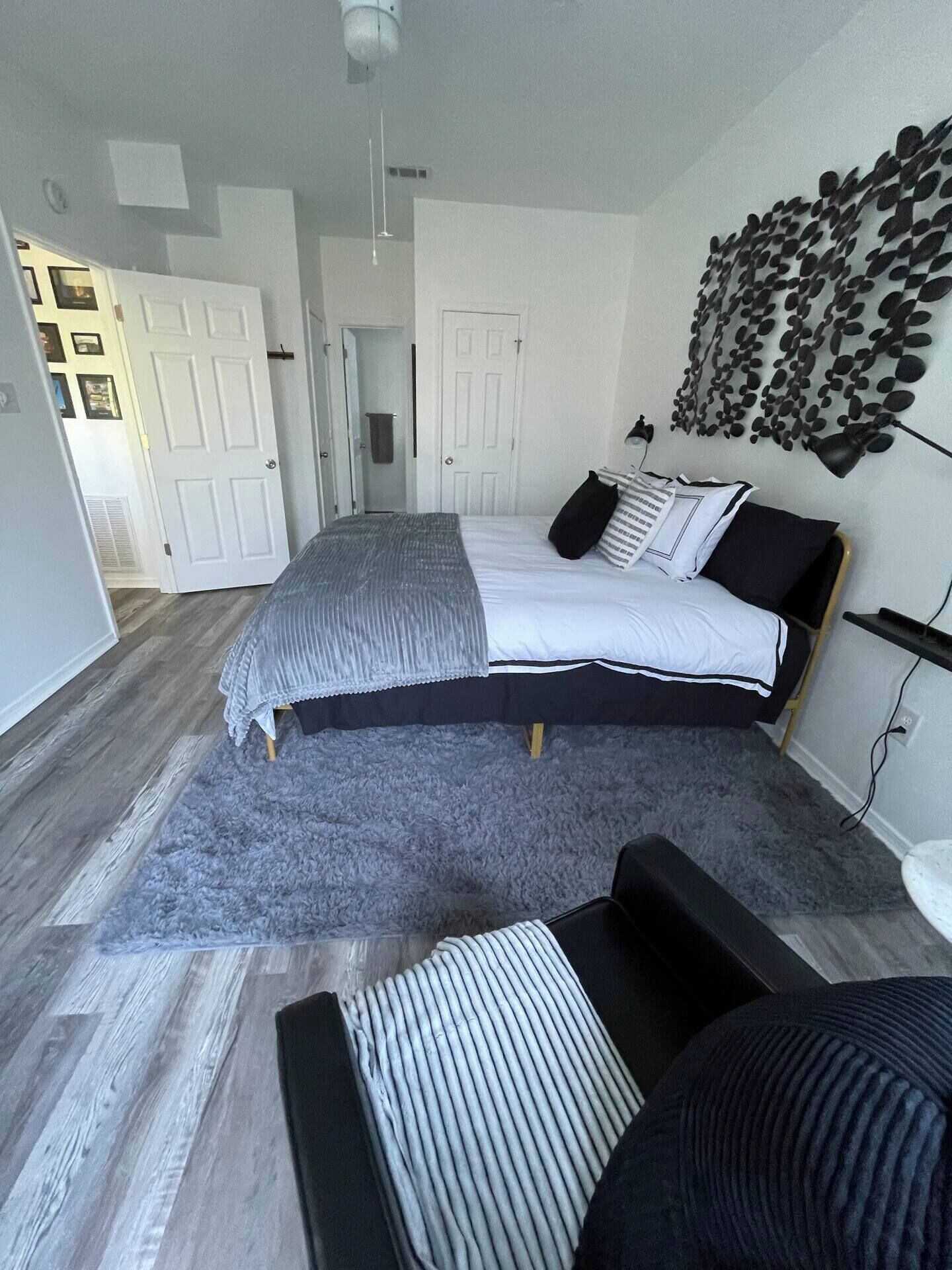 Une chambre à coucher moderne avec un grand lit, un tapis gris et un luminaire fixé au mur.