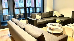 Un salon moderne avec un canapé d’angle, une table basse et un téléviseur.