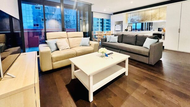 Un salon moderne avec un canapé, une table basse et un espace cuisine visible à travers une cloison en verre.
