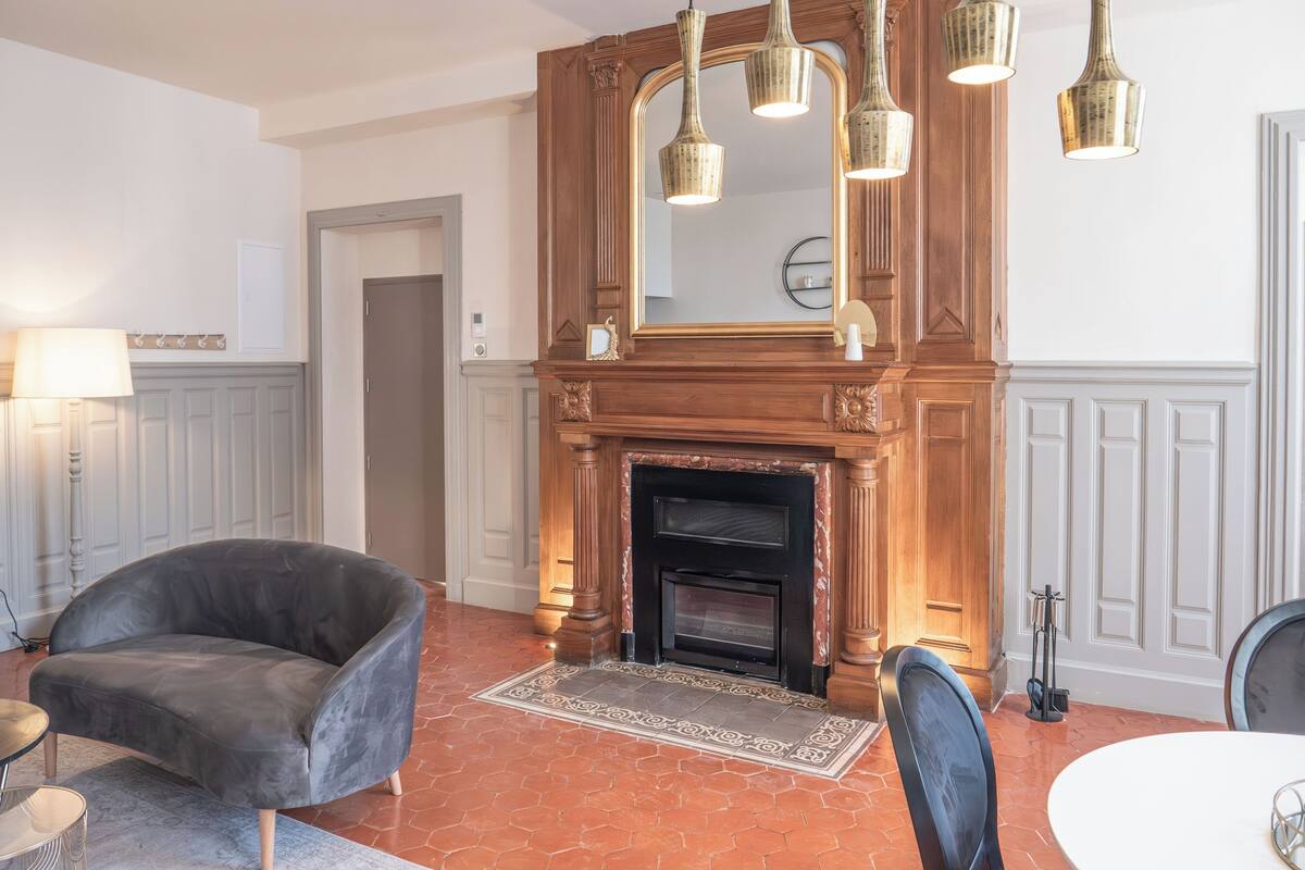 A room with a fireplace, a sofa, a dining table, and a mirror.