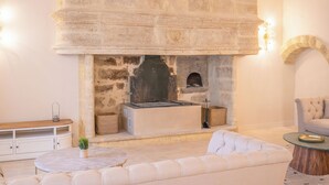 A stone fireplace with a built-in oven, a cushioned seating area, and a wooden bench.