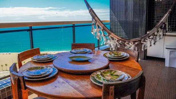 A round wooden table with plates and a hammock.