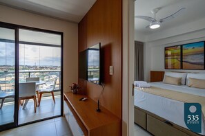 Habitación de hotel con balcón, cama, escritorio y televisor.