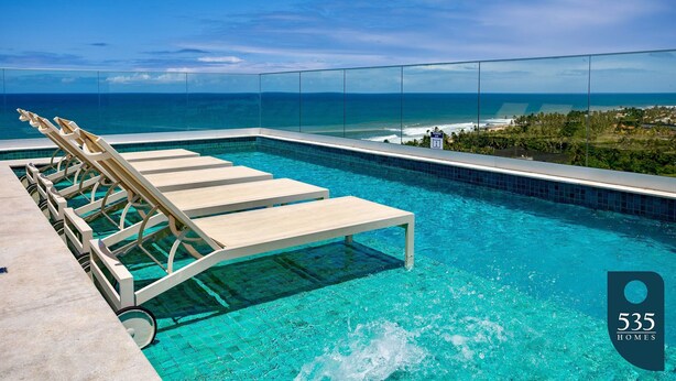 Zona de piscina amb gandules i vista a l'oceà.