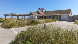 Een strandhuis met een overdekte veranda, een vlag en een garage.