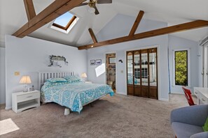 A bedroom with a bed, nightstands, a desk, a chair, a ceiling fan, a skylight, and a sliding glass door leading to a balcony. - 8 Sandy Neck- Family Getaway Near Sandy Neck Beach, pet-friendly! (Sandwich)