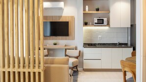 Una cocina moderna con armarios blancos, un microondas y un horno empotrado. Hay un comedor con una mesa y sillas.