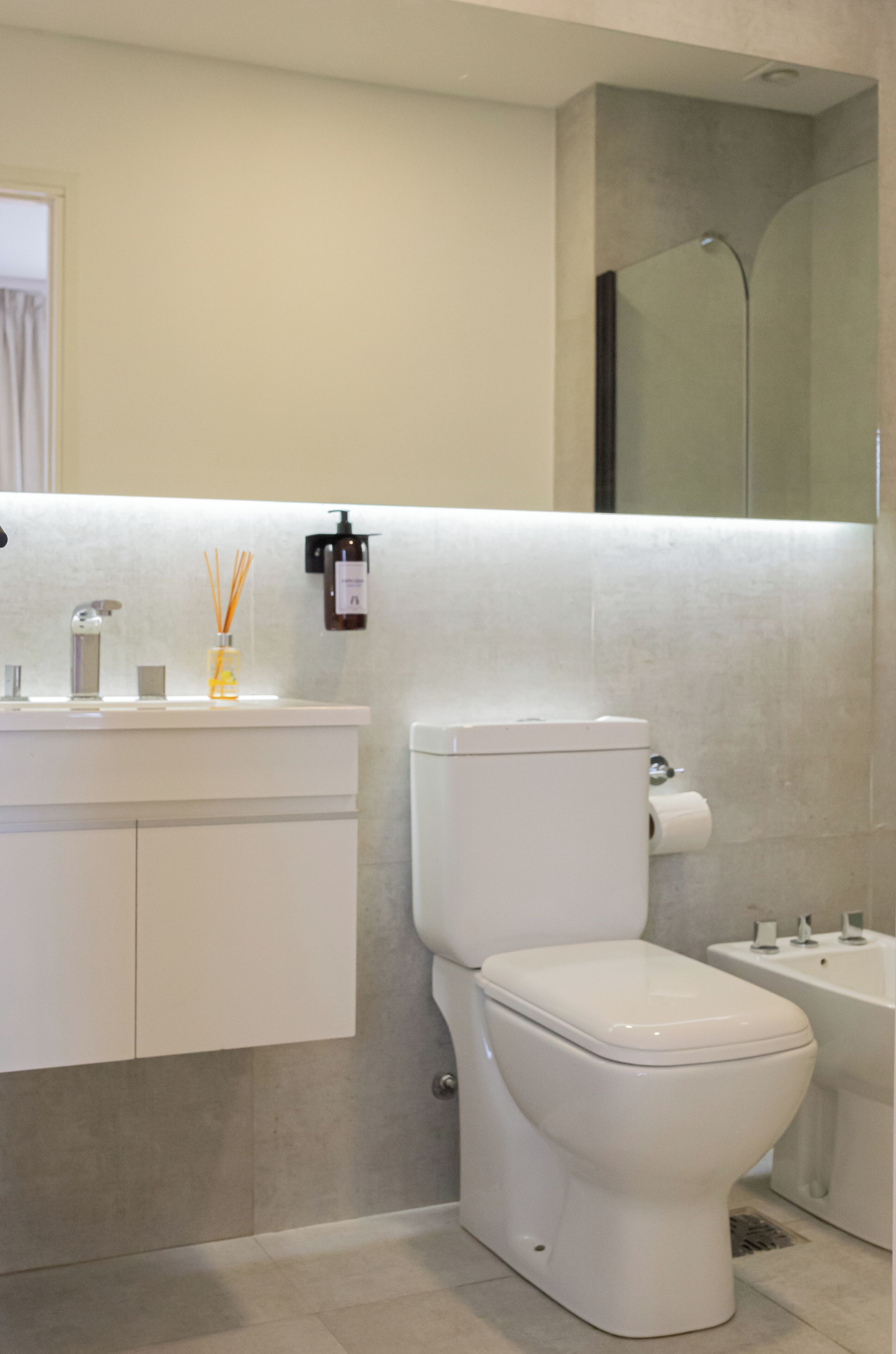 Een moderne badkamer met toilet, wastafel en douche.