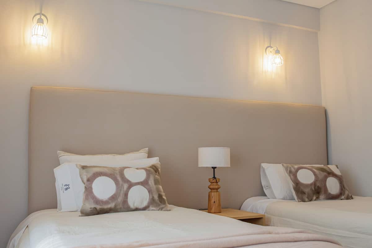 Une chambre d’hôtel avec deux lits, chacun doté d’une tête de lit, d’une table de chevet et d’une lampe.