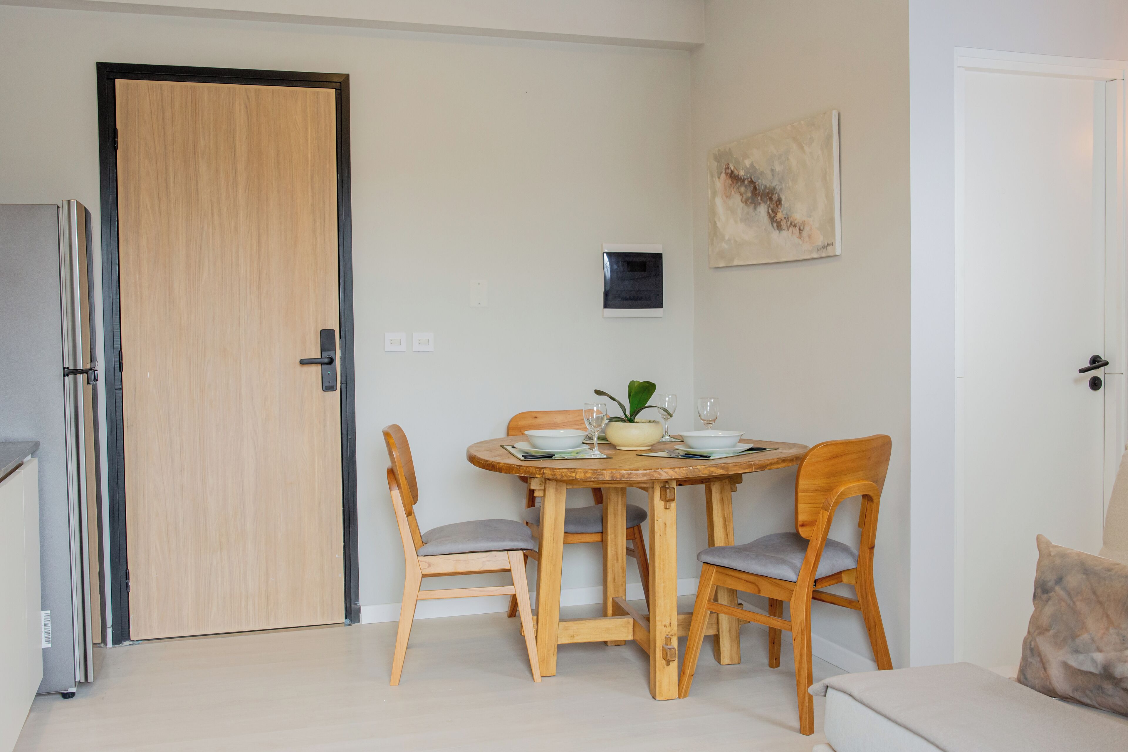 Un comedor con una mesa y sillas de madera, un refrigerador y una puerta.