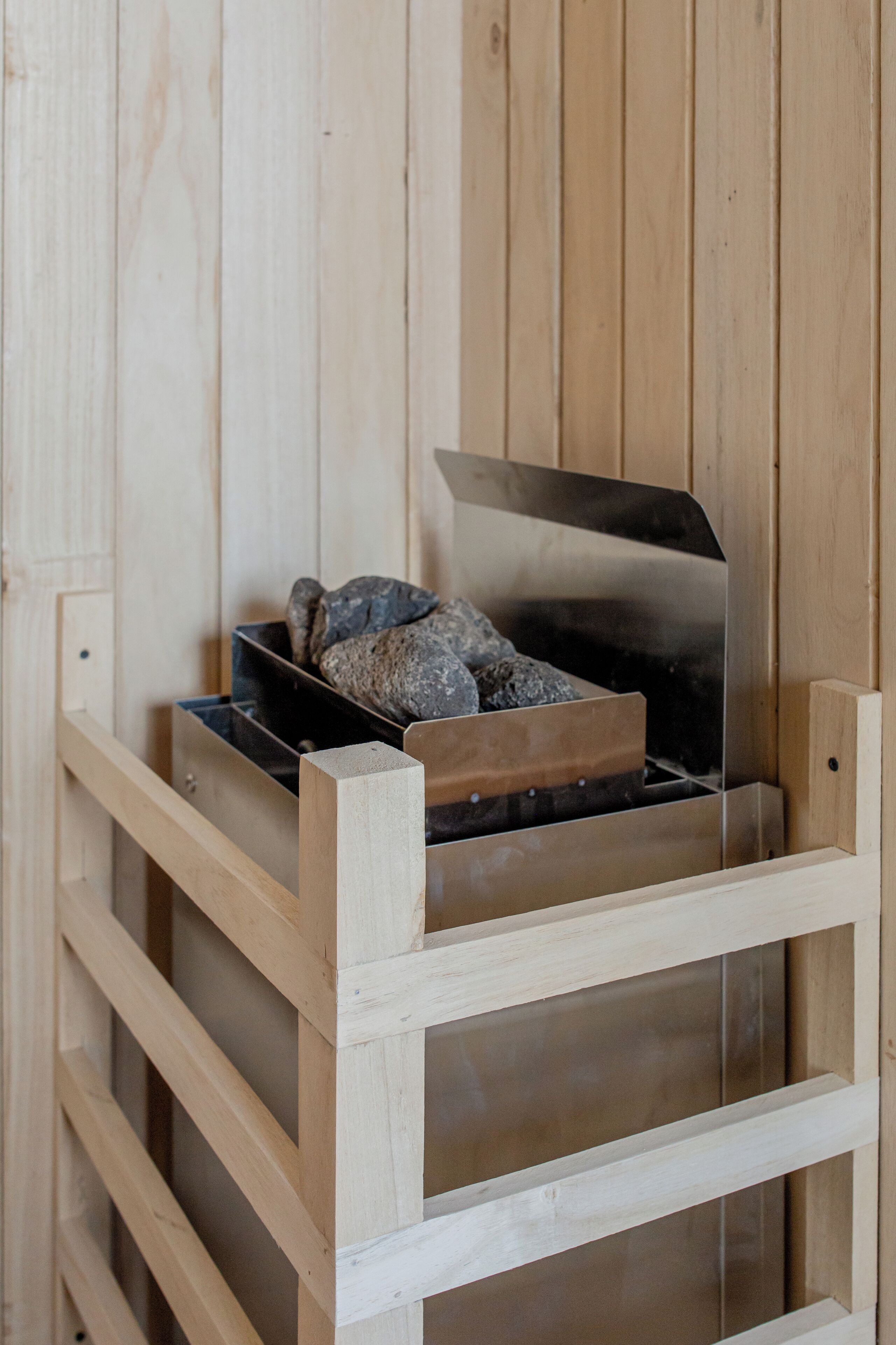 Un mueble de almacenamiento de madera con un estante metálico que sostiene varias rocas de color oscuro.