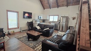 Un saló acollidor amb una llar de foc, un sofà, una taula de centre i un televisor.